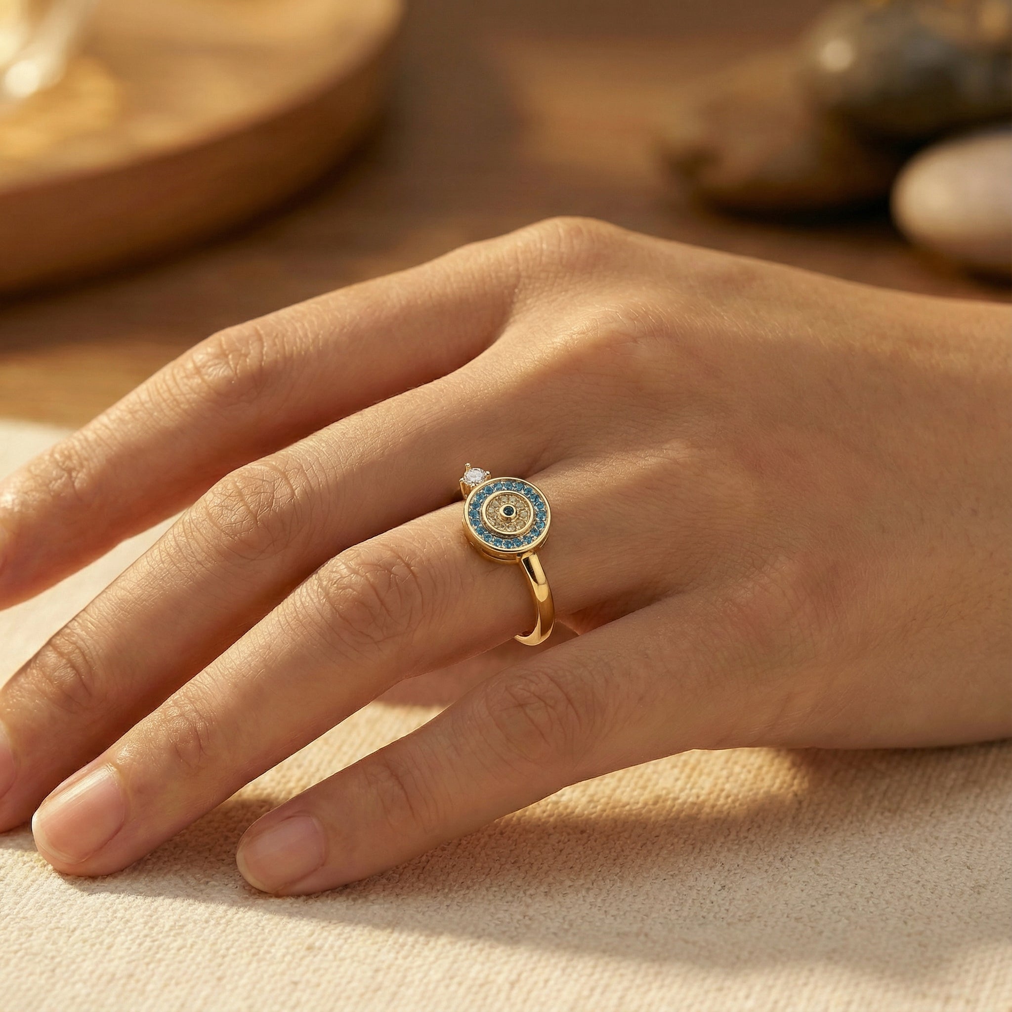 Bague dorée Onde Azur Holiseeds portée sur la main, détail du motif circulaire et des pierres.